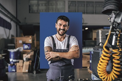 Ein Unternehmer steht in seiner Werkstatt. Man sieht viele Maschinen im Hintergrund.