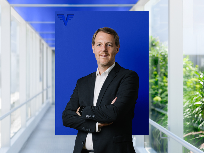 Tomas Kneifel vor blauem Hintergrund.