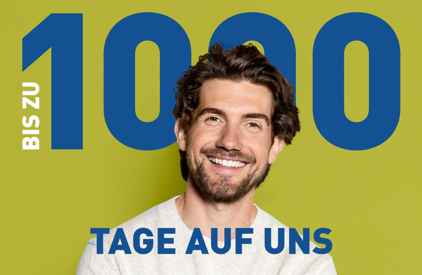 Ein Mann mit gewellten Haaren und Vollbart lächelt in die Kamera.