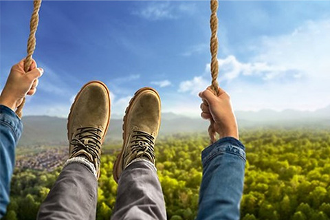 Wanderschuhe einer Person mein Schaukeln mit Sicht über eine grüne Waldlandschaft.