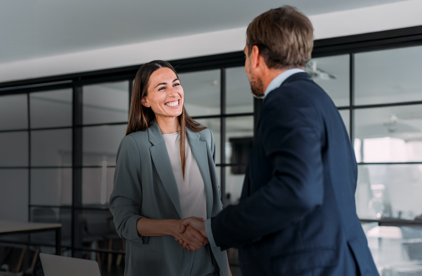 Eine Frau und ein Mann im Business-Outfit schütteln sich die Hand.
